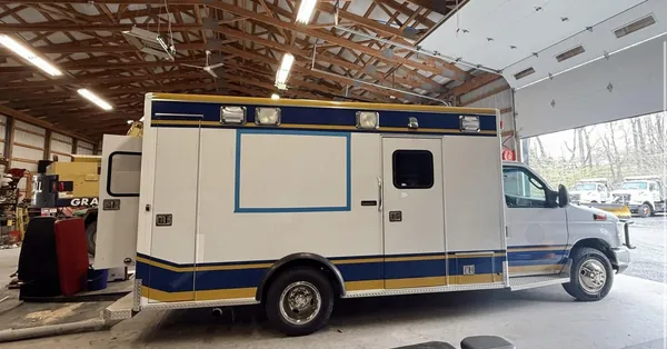 The ambulance in a workshop with the new service window marked out in blue tape on its side
